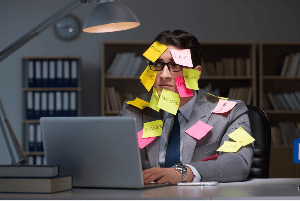 A man covered with sticky notes in front of a laptop